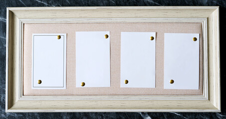 Obraz na płótnie Canvas Blank white papers on brown vintage wooden frame hanging on black and white marble wall background, copy space for text, mock up, template, banner