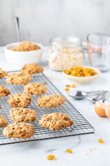 Oatmeal raisin cookies on a cooling rack surrounded by the recipe ingredients.