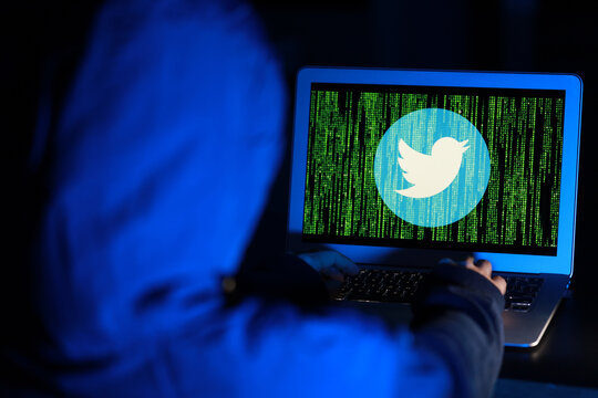 A hacker with computer hacking and stealing data information, Twitter logo and binary code as background. Twitter security and privacy issues. PENANG, MALAYSIA - 16 JULY 2020.