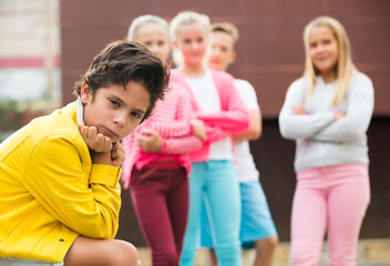 Portrait of boy 9-12 years old who is taking offense on his friends in the park.
