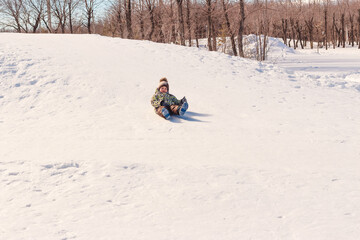 Fototapeta na wymiar boy on sled ice rides from the hill in winter