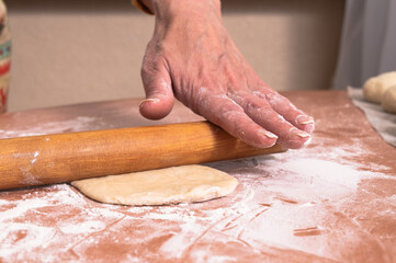 The woman rolls out a small dough cake. homemade baking