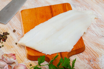 Raw Atlantic halibut fillet on wooden table with condiments. Seafood delicacy