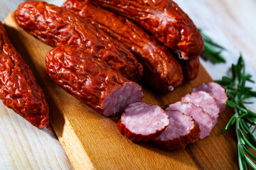 Appetizing hot smoked pork sausages on wooden surface with herbs. Traditional Czech recipe