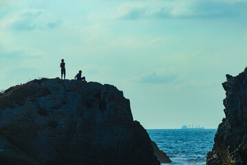 two friends on a rock in the sea
