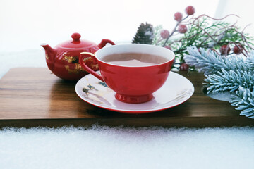 tea in a cup and teapot on a blackboard in the snow in winter