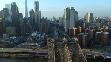 Cinematic aerial rotating over Brooklyn Bridge and overlooking stunning Manhattan skyline and buildings on sunny summer day in New York City, USA.