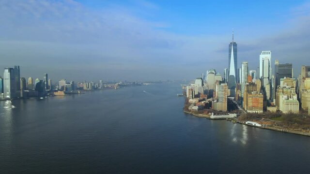 Aerial flying sideways from New Jersey, Jersey City to downtown Manhattan with stunning One World Trade Center filmed from Hudson River on sunny summer day in New York City, USA.