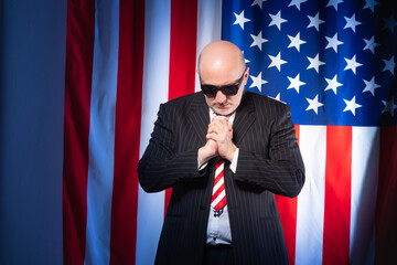 Man prays on background of American flag. He works as lobbyists America. Employee of a lobbying...