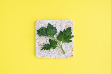Healthy snack Crunchy crispbread with fresh parsley leaves. Yellow background, copy space.