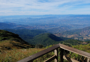 Wooden viewpoint spot with green mountains and cloudy blue sky