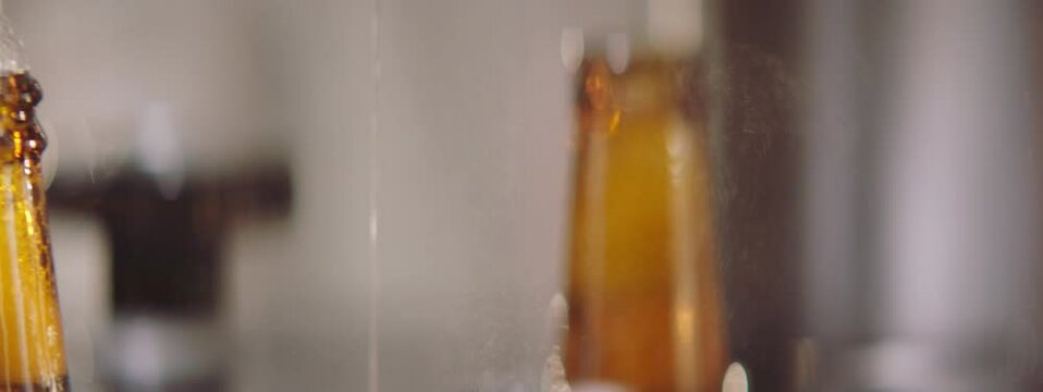 Slow motion, close-up video of brewing process in a brewery. Beer bottles moving along the conveyor belt. Factory, brewery concept.