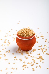 Wheat grains in clay pot on white background