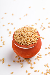 Wheat grains in clay pot on white background