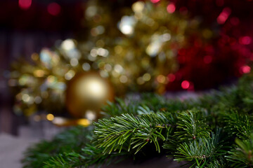 Winter background for New Year and Christmas, fir branches, tinsel, Christmas tree decoration, orange beads, blurry lights.