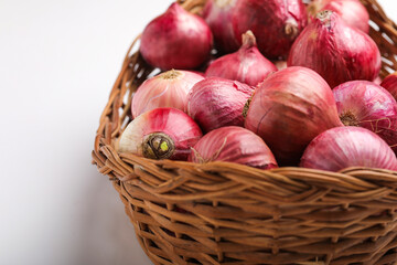 Obraz na płótnie Canvas Red onions in wooden basket on white background