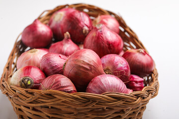 Red onions in wooden basket on white background