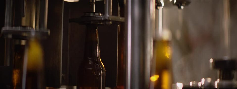 Slow motion, close-up video in a brewery. Beer glass bottles moving on a modern machinery in a factory. Factory, brewery concept.