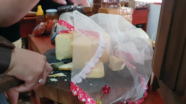 Cutting a slice of cheese for the store customer to taste. Queijo Mineiro cheese, from Brazil.
