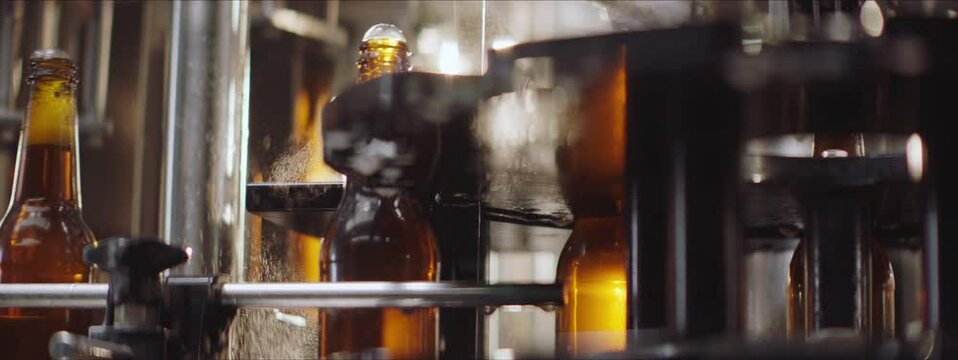 Full beer bottles moving on a modern machine in a factory. Beer bottles ready for capping machine. Factory, brewery concept.