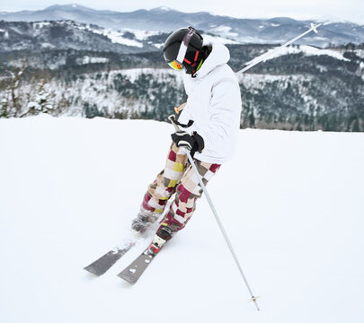 Image of skier in ski equipment, captured in motion doing trick in snowy mountains in full length. Beautiful landscape on background. Winter sports concept