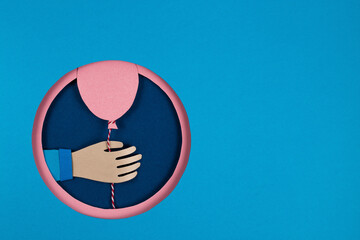 Hand holding a pink paper balloons in overlap blue round hole, pink circle frame. Holiday, birthday, valentine concept. 3D Paper art and origami style. Celebrate events banner posters