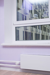plastic window and white window sill with white battery and heating temperature controller, background
