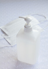 白いレースの布の上に置かれた手指消毒用アルコール液とマスク