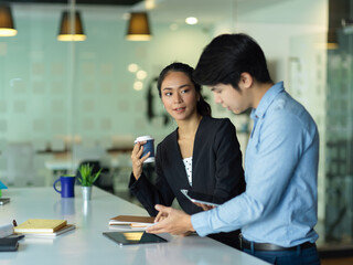 Businesswoman and businessman talking to each other while consulting on their work