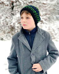 Portrait of preteen kid boy outdoors. Handsome child boy in coat and hat in winter.