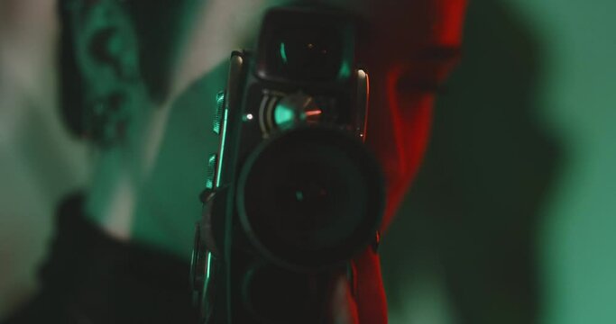 Young caucasian woman with piercing filming with a retro camera in a studio 