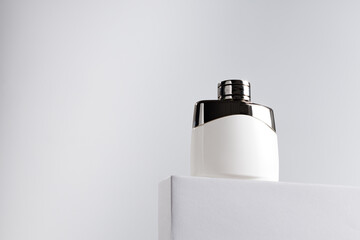 Fragrance bottle on gray block against gray background