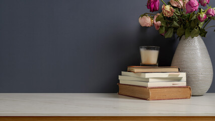 Workspace with books, flowers vase, candle and copy space on marble desk