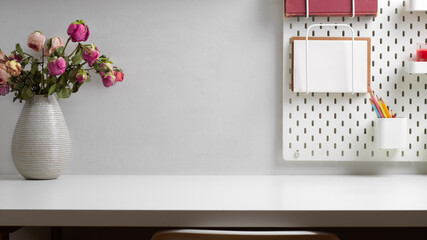 Home office desk with copy space, flower vase and stationery on shelf