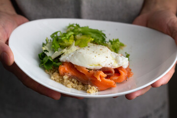 quinoa with fish and egg for breakfast in male hands close-up
