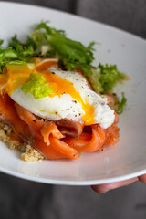 quinoa with fish and egg for breakfast in men's hands
