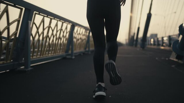 Follow Camera Angle From The Side Back. White Skin Asian Women Wearing A Black Sports Bra And Black Pants. Jogging On The Bridge In The Middle Of The City In The Morning Or The Evening 