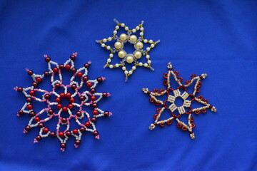 Beautiful snowflakes made of beads on a blue background. Handmade.