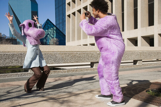 Man in bottom part of hippo costume taking picture of a woman wearing hippo mask