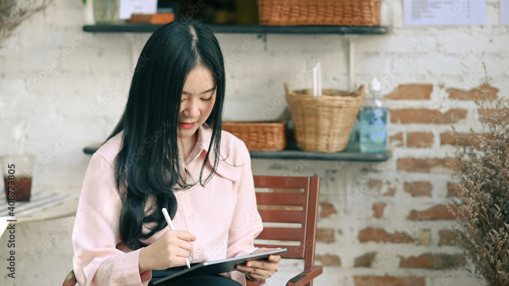 Wall mural young female designer using stylus pen drawing on digital tablet while sitting at comfortable workpl