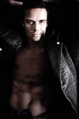 Semi naked handsome man sitting in leather armchair with open shirt revealing sixpack abs and open...