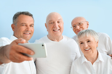 Senior people taking selfie on color background