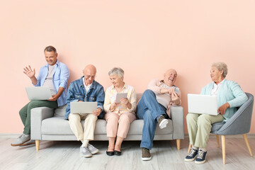 Senior people with different devices sitting on sofa in room