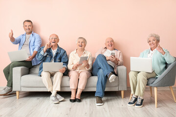 Senior people with different devices sitting on sofa in room