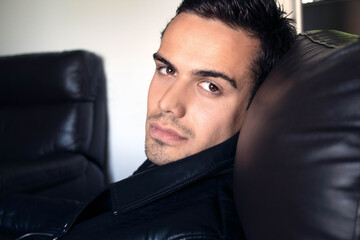 Semi naked handsome man sitting in leather armchair with open shirt revealing sixpack abs and open...