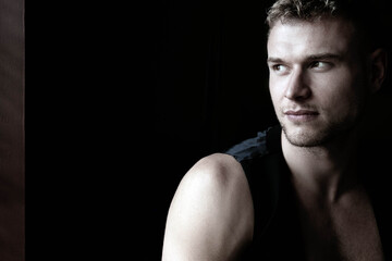 Naklejka premium Portrait of handsome young man looking away from camera with open black shirt revealing muscular pecs