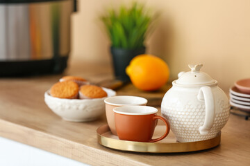 Tray with teapot and cups of tea on kitchen table