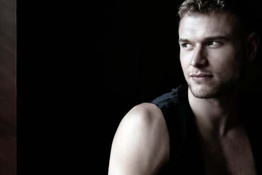 Portrait of handsome young man looking away from camera with open black shirt revealing muscular pecs