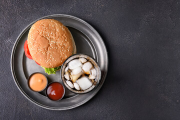Tray with tasty burger, sauces and cola drink on dark background