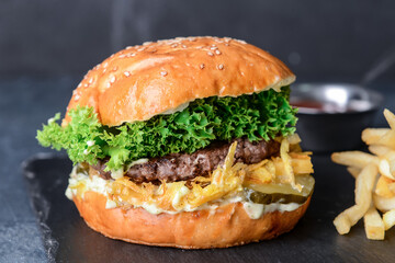 Board with tasty burger on dark background
